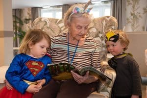 Statham Manor resident Sylvia Griffiths reading to children from Back to the Garden Childcare